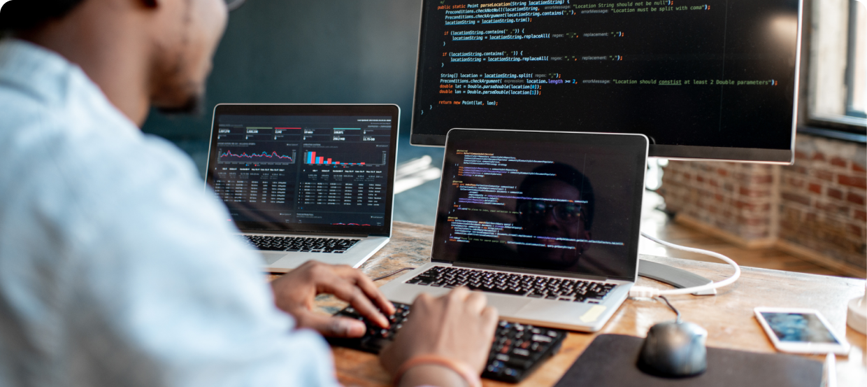 man with glasses developing app with 3 monitor 