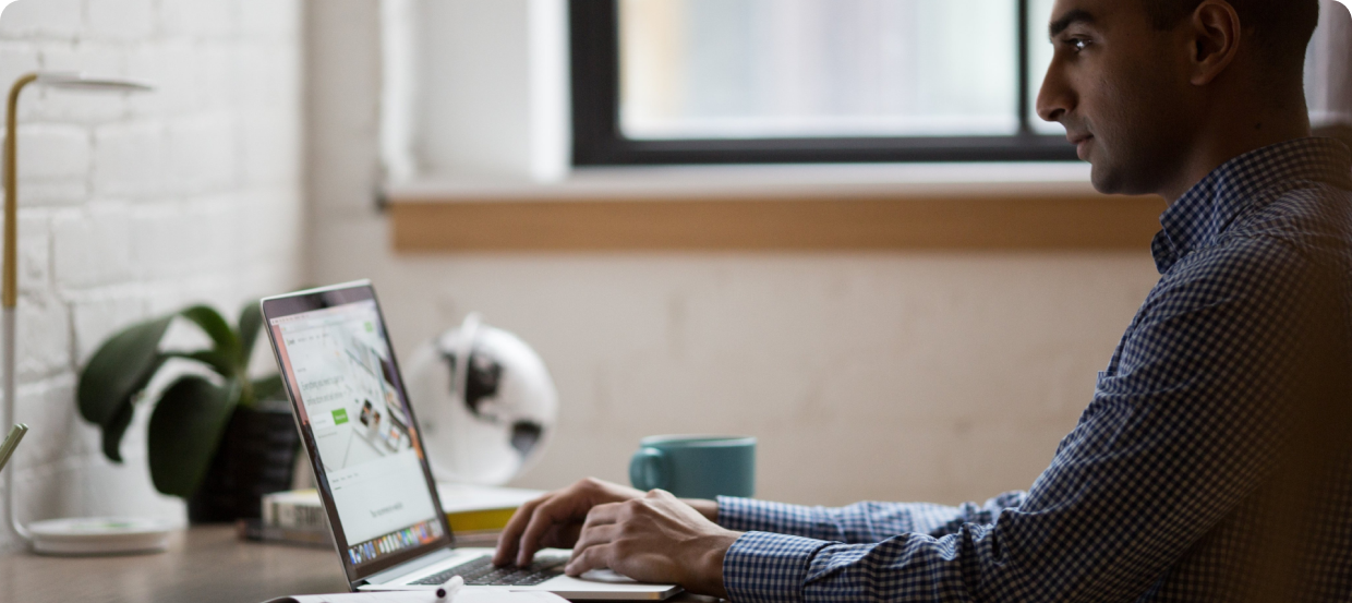 a side angle man smiling in front of his laptop 